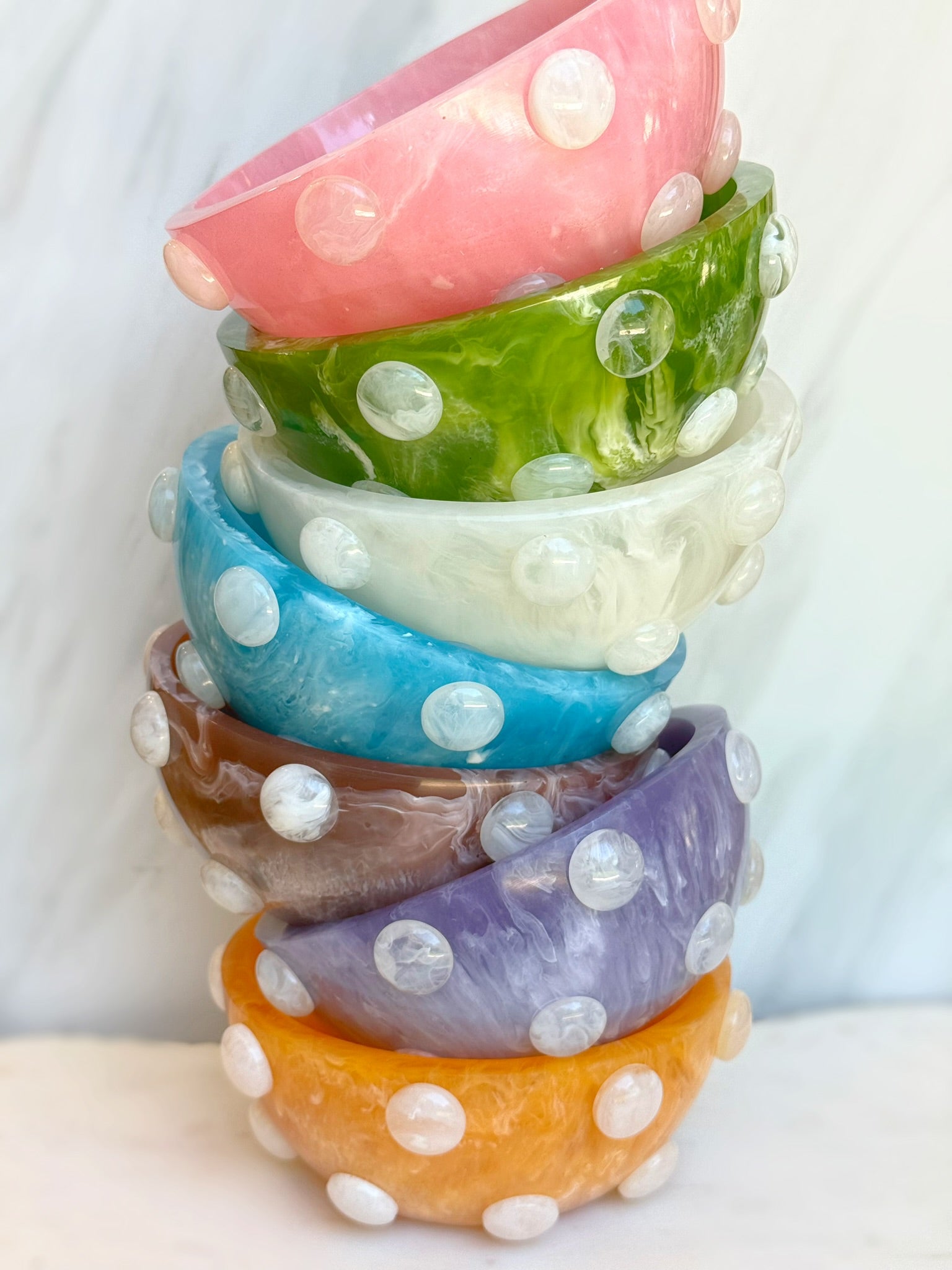 Stack of colorful bowls with polka dot patterns on a white background